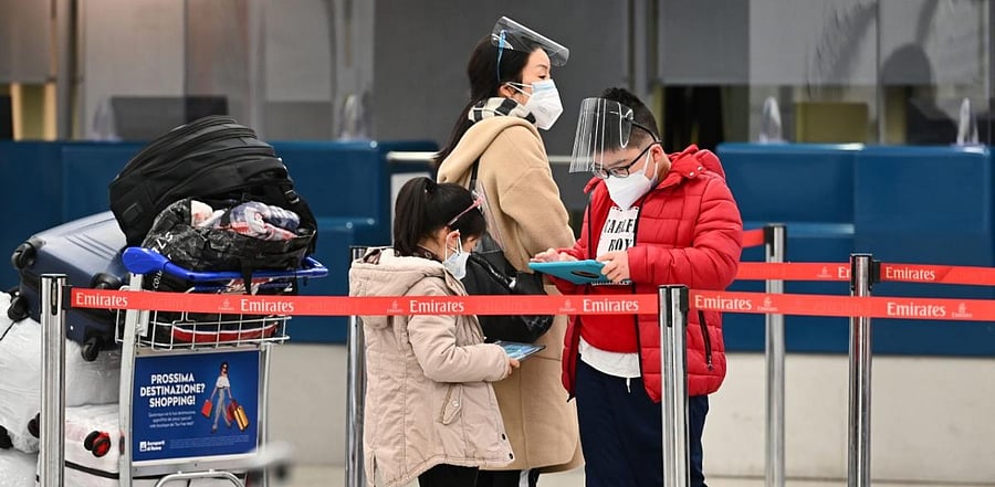 Passengers wearing a face mask and a face shield wait to check in on December 9, 2020 at Rome's Fiumicino airport. Credit: AFP Photo
