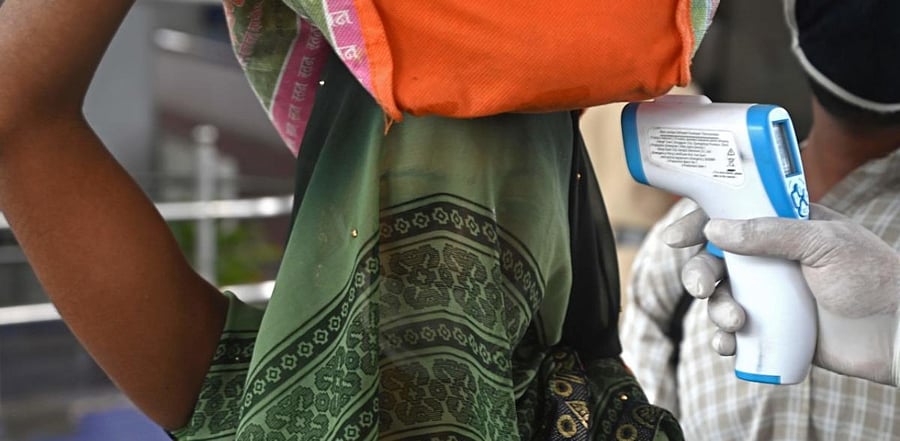 A health worker checks the body temperature of a train passenger upon her arrival during the mandatory Covid-19 coronavirus screening at a railway terminus in Mumbai on December 9, 2020. Credit: AFP Photo