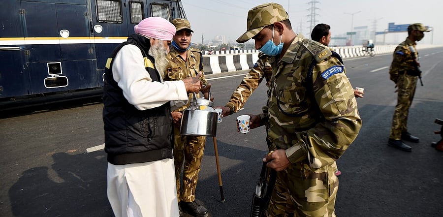 A farmer offers tea to security personnel at Ghazipur border during 'Delhi Chalo' protest march against the new farm laws, in New Delhi. Credit: PTI Photo