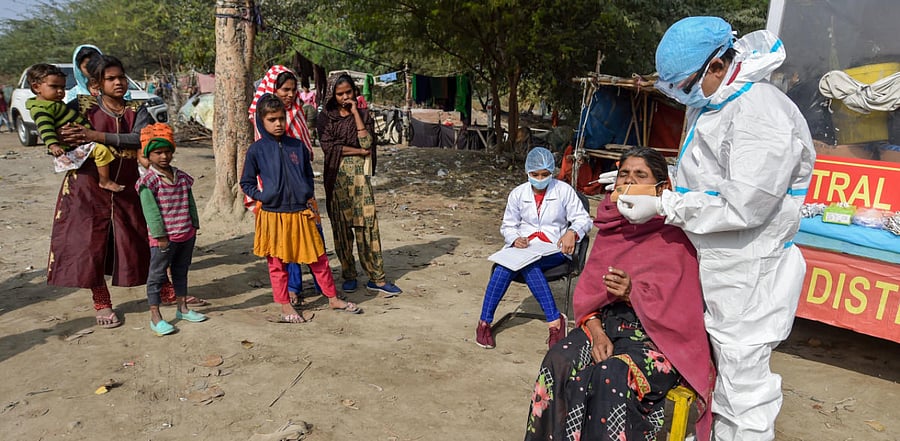 A health worker wearing protective gear collects swab sample for Covid-19 test at Baila Gaon Jhuggi Basti in New Delhi. Credit: PTI Photo