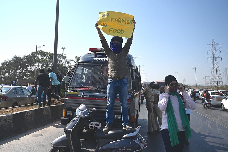 A protester holding a poster stands on top of a scooter while blocking a highway during a nationwide general strike called by farmers to protest against the recent agricultural reforms in Mumbai on December 8, 2020. Representative image/Credit: AFP Photo
