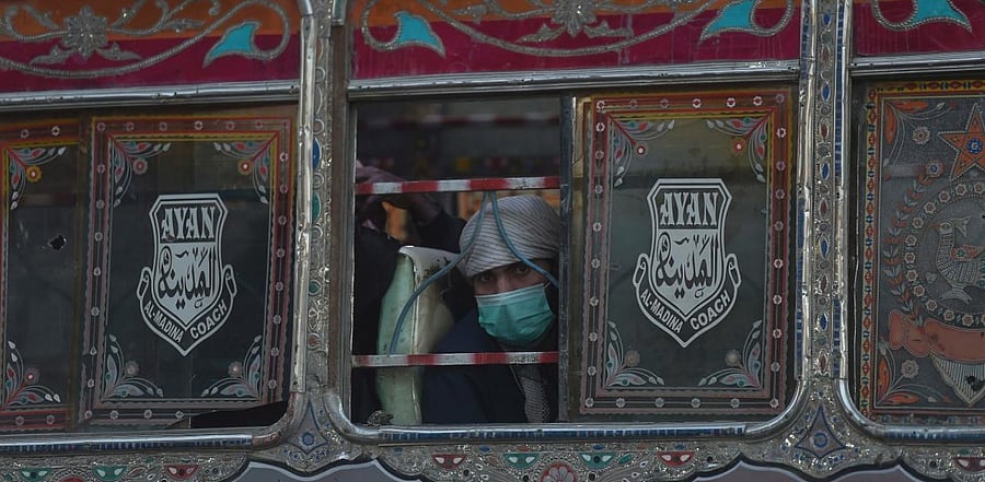 A man wearing a facemask as a preventive measure against the Covid-19 coronavirus, travels on a passenger bus in Karachi. Credit: AFP.