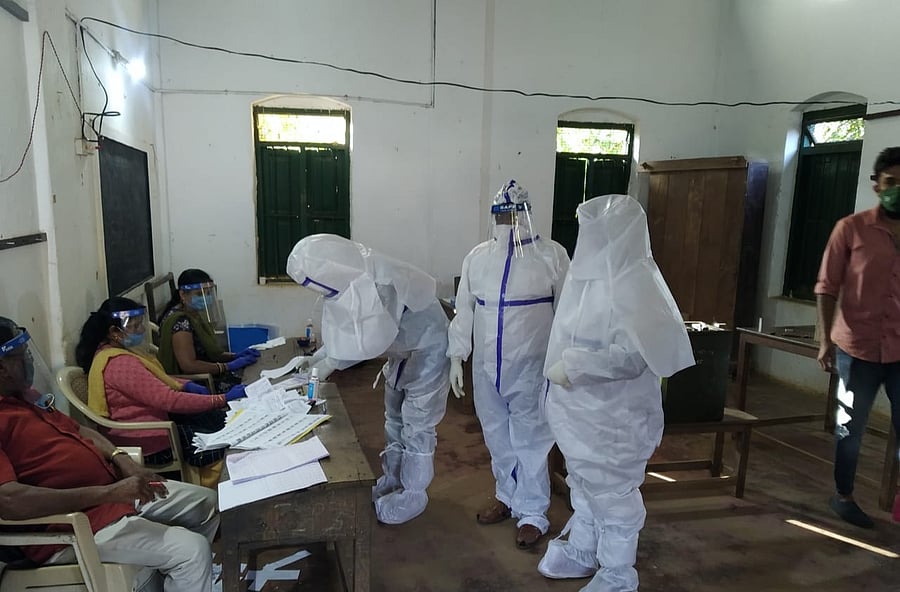 PPE-clad Covid positive voters exercise their franchise at a polling booth in Kodagu district during the gram panchayat. Credit: DH Photo