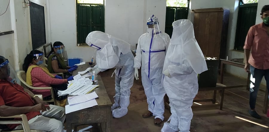 PPE-clad Covid positive voters exercise their franchise at a polling booth in Kodagu district during the gram panchayat elections on Tuesday. Credit: DH Photo