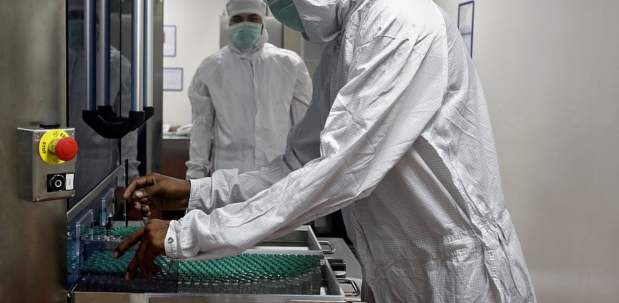 An employee in personal protective equipment (PPE) removes vials of AstraZeneca's COVISHIELD, coronavirus disease vaccine from a visual inspection machine inside a lab at Serum Institute of India, Pune. Credit: Reuters Photo