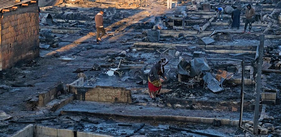 Syrian refugees salvage belongings from the wreckage of their shelters at a camp set on fire overnight in the northern Lebanese town of Bhanine. Credit: AFP Photo
