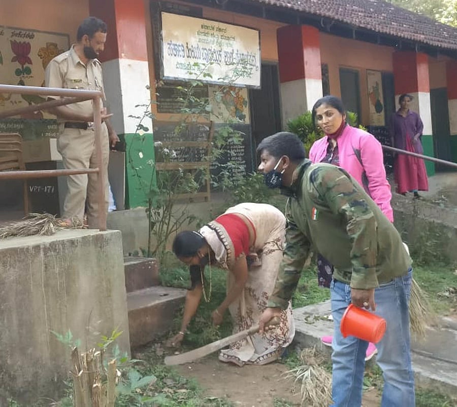 Polling officials clean the premises of the Government Higher Primary School at Hebbale.