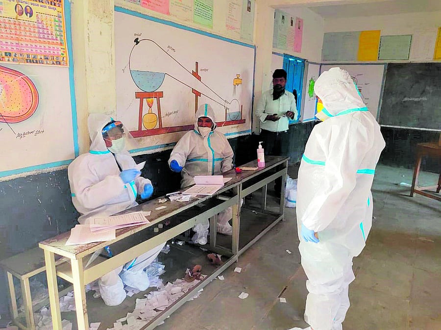 A Covid patient wearing PPE kit prepares to cast vote at Devoora booth in Vijaypura district. DH Photo