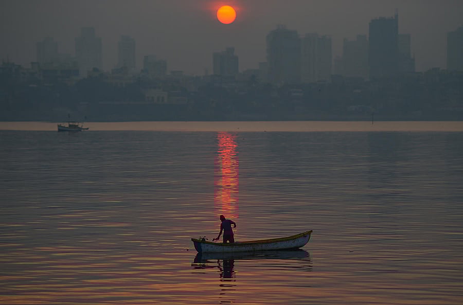 A fisherman fishes in the sea water as smog engulfs the city skyline, in Mumbai, Saturday, Dec. 26, 2020. Credit: PTI Photo