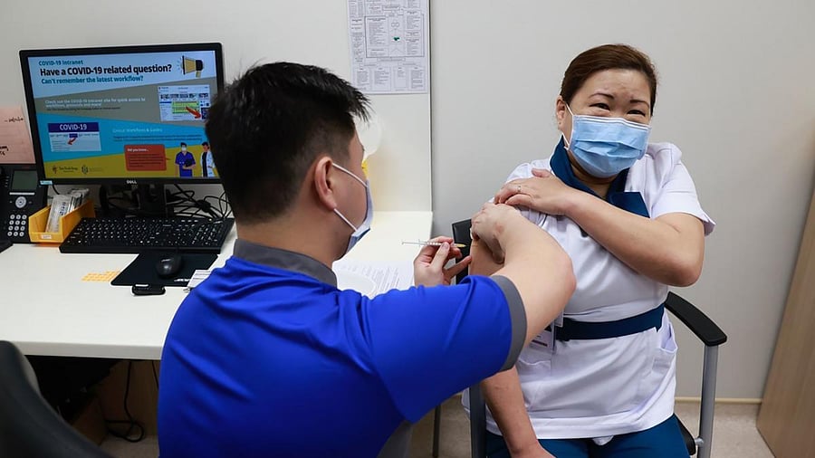 Senior staff nurse Sarah Lim of Singapore's National Centre for Infectious Diseases (NCID) receives a Covid-19 vaccination, administered by senior staff nurse Kho Wei Lian (L), at the NCID Day Treatment Centre in Singapore. Credit: AFP