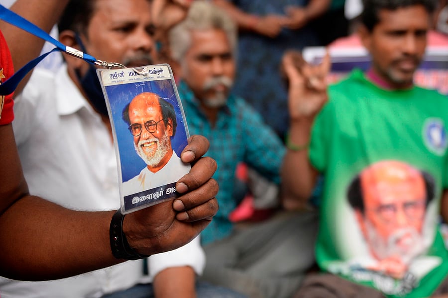 A fan of actor Rajinikanth holds his picture next to others near Rajinikanth's residence asking him to enter politics the day after he cancelled his political plans, in Chennai on December 30, 2020. - Indian movie superstar Rajinikanth on December 29 cancelled his plans to enter politics, saying a health scare had been "a warning from god". Credit: AFP Photo