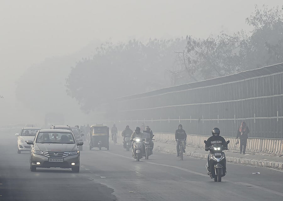 Vehicles move slowly on a street, amid dense fog, on a cold morning in New Delhi. Credit: PTI.