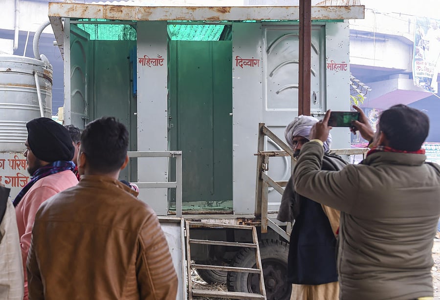 People gather outside a restroom where farmer Sardar Kashmir Singh allegedly hanged himself during a protest against the new farm laws, at Ghazipur border in New Delhi, Saturday, Jan. 02, 2021. Credit: PTI Photo