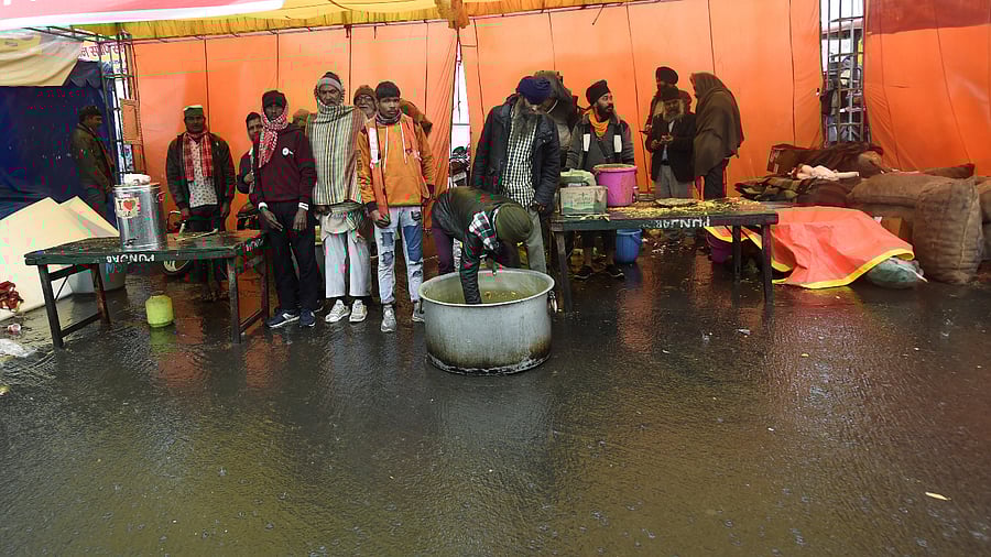 Farmers take shelter In a tent as it rains during their ongoing protest against the new farm laws at Ghazipur Border. Credit: PTI Photo