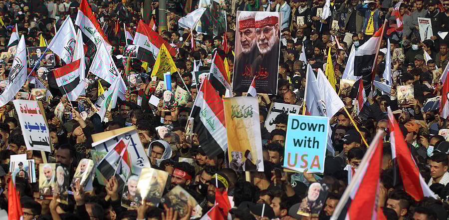 Iraqi demonstrators lift flags and placards as they rally in Tahrir square in the capital Baghdad to mark a year of the killing of Qasem Soleimani. Credit: AFP Photo
