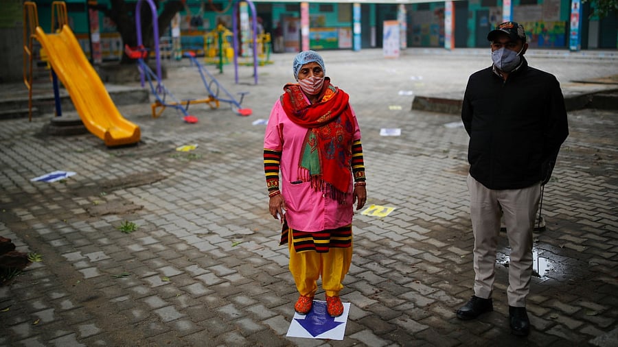 A volunteer waits during a nationwide trial run of coronavirus vaccine delivery systems, inside a school, which has been converted into a temporary vaccination centre, in New Delhi on January 8, 2021. Credit: Reuters Photo
