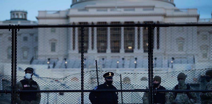 A Capitol Police officer stands with members of the National Guard behind a crowd control fence surrounding Capitol Hill a day after a pro-Trump mob broke into the US Capitol. Credit: AFP Photo