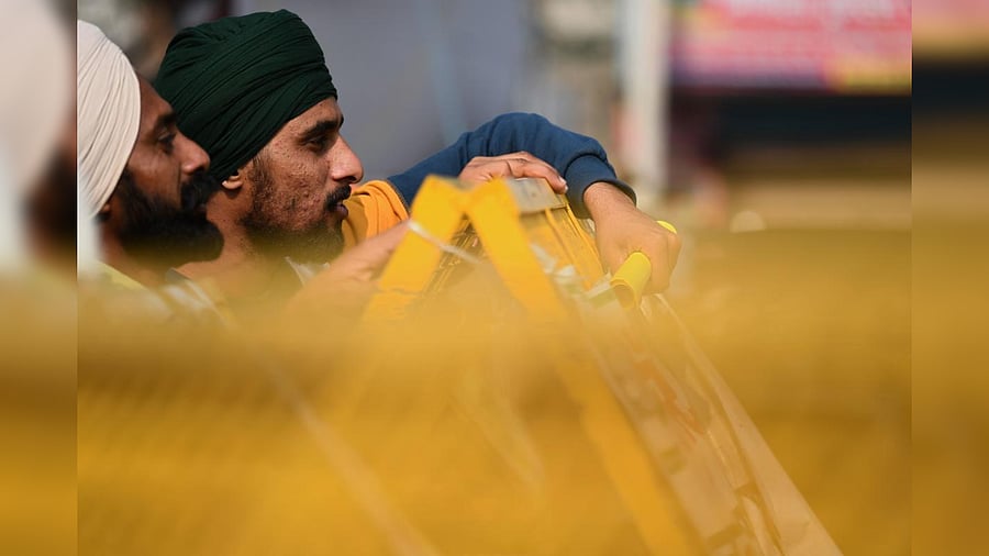 Farmers stand behind a police barricade as they take part in a protest against the central government's recent agricultural reforms at Tikri border in New Delhi on December 26, 2020. Credit: AFP Photo