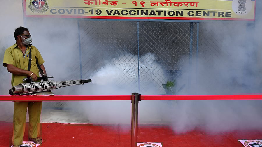A civic authority worker fumigates a Covid-19 coronavirus vaccination centre as a preventive measure against diseases-carrying mosquitoes in Mumbai. Credit: AFP Photo.