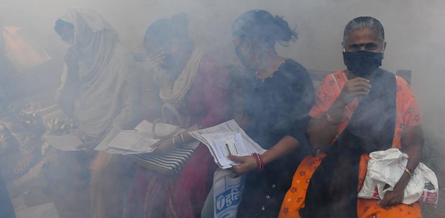 Patients at a nearby hospital react as a civic authority worker fumigates a Covid-19 coronavirus vaccination centre as a preventive measure against diseases-carrying mosquitoes in Mumbai on January 16, 2021. Credit: AFP Photo