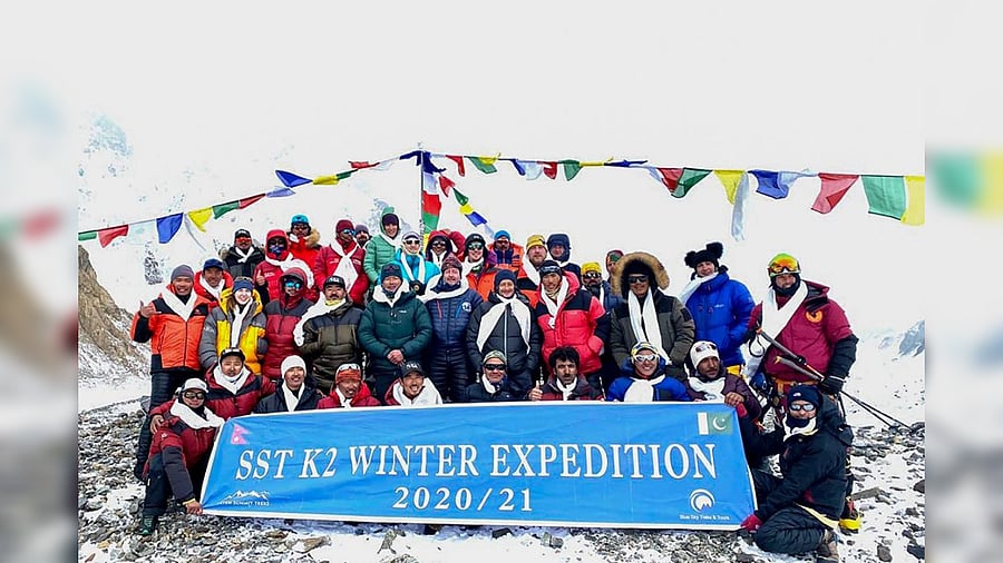 This handout photo taken on January 16, 2021 and released by Seven Summit Treks, shows mountaineers and Sherpas posing for pictures after reaching the summit of Mt K2, which is the second highest mountain in the world, at the Base Camp of the winter expedition in the Gilgit-Baltistan region of northern Pakistan. Credit: AFP