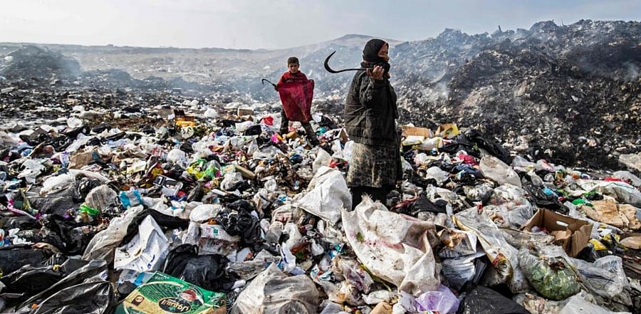 Syrians sift through a garbage dump near an oil field in the countryside of Malikiya in northeast Syria, on January 12, 2021. Credit: AFP Photo