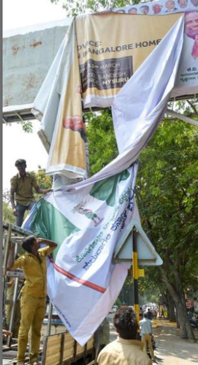 Mysuru City Corporation personnel remove flex posters in Mysuru recently. Dh file photo