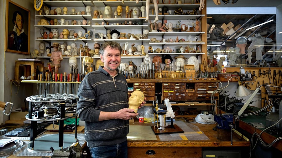 A picture taken on January 19, 2021 shows Swiss master Francois Junod posing with his tools and some heads used for the molding of parts of moving mechanical artworks, in his workshop in Sainte-Croix