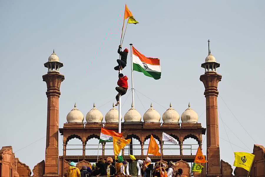 Protesters climb a flagpole at the ramparts of the Red Fort as farmers continue to demonstrate against the central government's recent agricultural reforms in New Delhi on January 26, 2021. Credit: AFP Photo