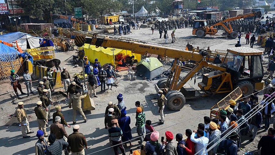 Farmers (R) watch as police (C) set up road blocks at the Delhi-Haryana state border in Singhu. Credit: AFP Photo