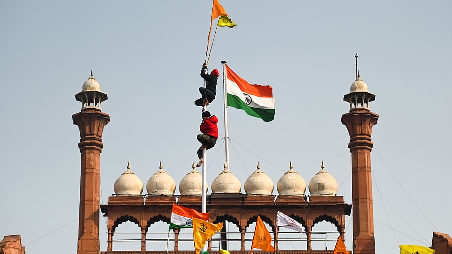 Protesters climb a flagpole at the ramparts of the Red Fort as farmers continue to demonstrate against the central government's recent agricultural reforms in New Delhi. Credit: AFP Photo