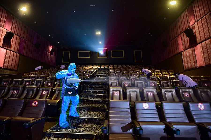 A worker wearing PPE kit sanitises a cinema hall, as mutilplexes prepare to re-open from tomorrow after nearly eight months of closure due to coronavirus lockdown, in Chennai. Credit PTI Photo