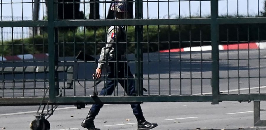 A policeman walks behind an area blocked by a gate near the international airport in Yangon on February 1, 2021, as Myanmar's military detained the country's de facto leader Aung San Suu Kyi and the country's president in a coup. Credit: AFP Photo