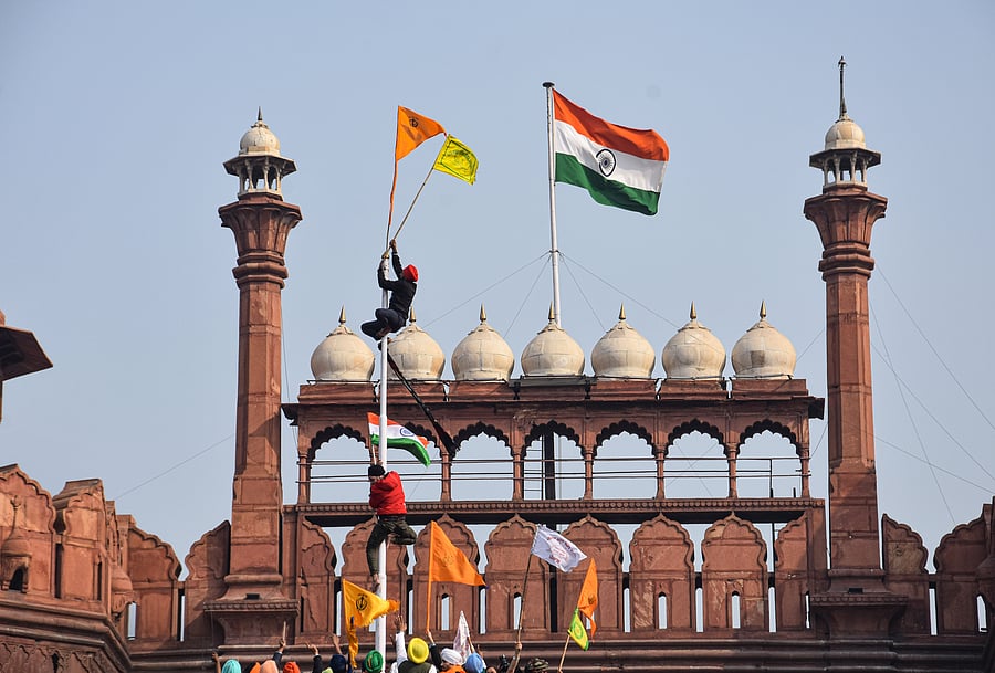 Farmers hoist flags at the Red Fort during the 'Kisan Gantantra Parade' amid the 72nd Republic Day celebrations, in New Delhi, Tuesday, Jan. 26, 2021. Credit: PTI Photo
