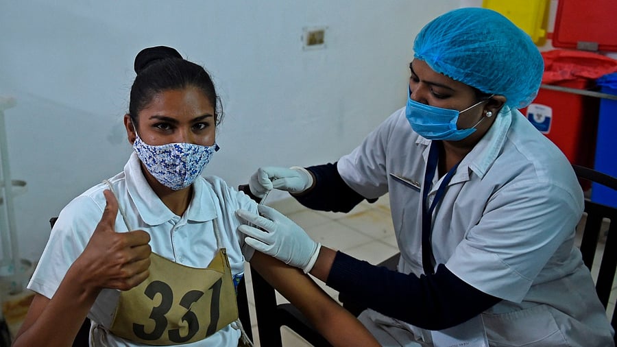 A health worker inoculates a Gujarat Police's Lok Rakshak Dal (LRD) personnel with a coronavirus vaccine at a civil hospital in Ahmedabad. Credit: AFP File Photo