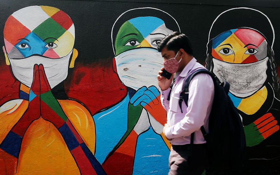 A man walks past a graffiti of people wearing protective masks amidst the spread of the coronavirus disease (COVID-19) on a street in Navi Mumbai, India January 21, 2021. Credit: REUTERS Photo