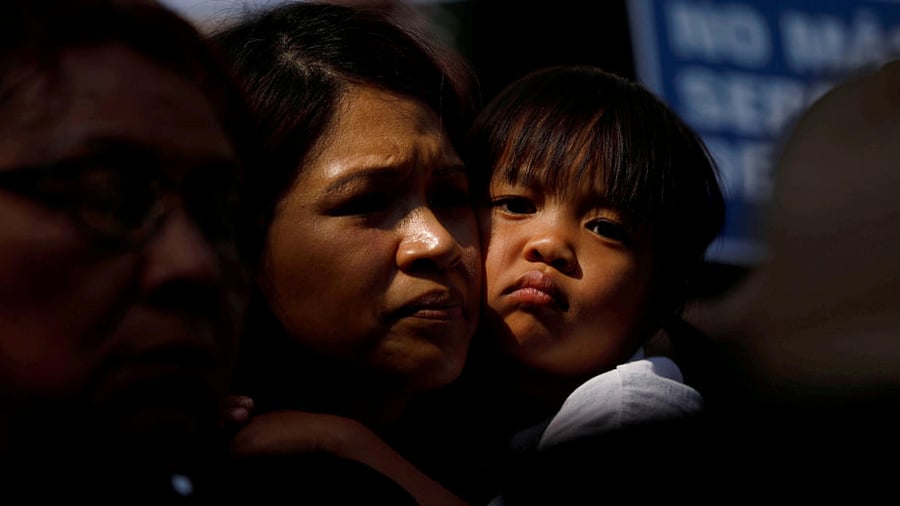 A child embraces a woman as people hold signs to protest against U.S. President Donald Trump's executive order to detain children crossing the southern U.S. border and separating families outside of City Hall in Los Angeles, California, U.S. June 7, 2018. Credit: Reuters Photo