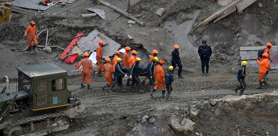 Members of National Disaster Response Force (NDRF) and State Disaster Response Fund (SDRF) carry the body of a victim after recovering it from the debris inside a tunnel during a rescue operation after a flash flood swept a mountain valley destroying dams and bridges, in Tapovan in the northern state of Uttarakhand. Credit: Reuters Photo