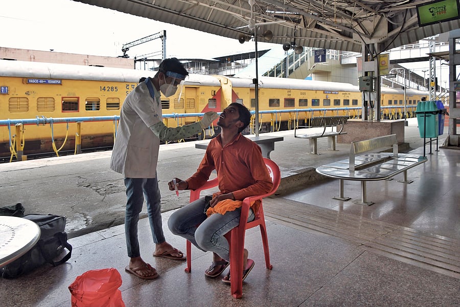 A health worker (L) takes a nasal swab from a passenger for a Covid-19 coronavirus test at Yeshwanthpur Railway Station, in Bangalore. Credit: AFP Photo