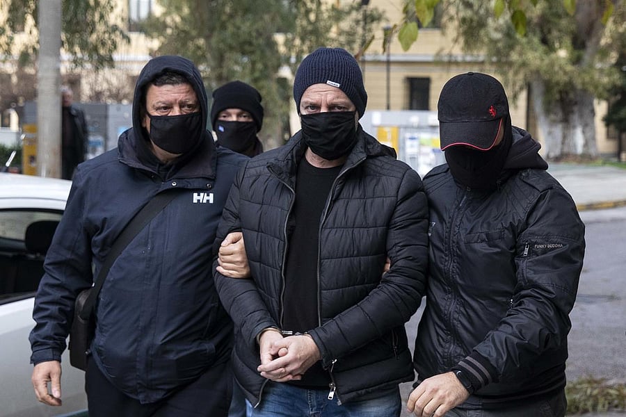 Plain-clothed policemen escort handcuffed well-known actor and director Dimitris Lignadis (C) to a magistrate's office in Athens. Credit: AP photo. 