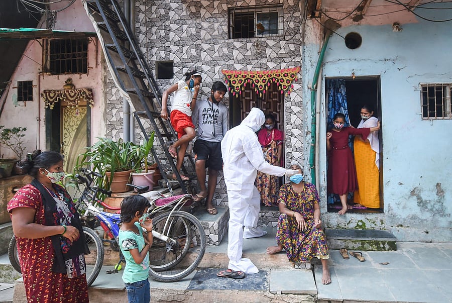 A BMC health worker wearing protective gear takes a swab sample of a woman for the Covid-19 test at Dharavi, in Mumbai. Credit: PTI photo. 
