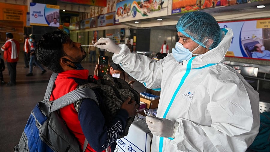A medical worker takes a swab sample from a passenger for a Rapid Antigen Test (RAT) Covid-19 coronavirus test at the railway station in New Delhi. Credit: AFP File Photo