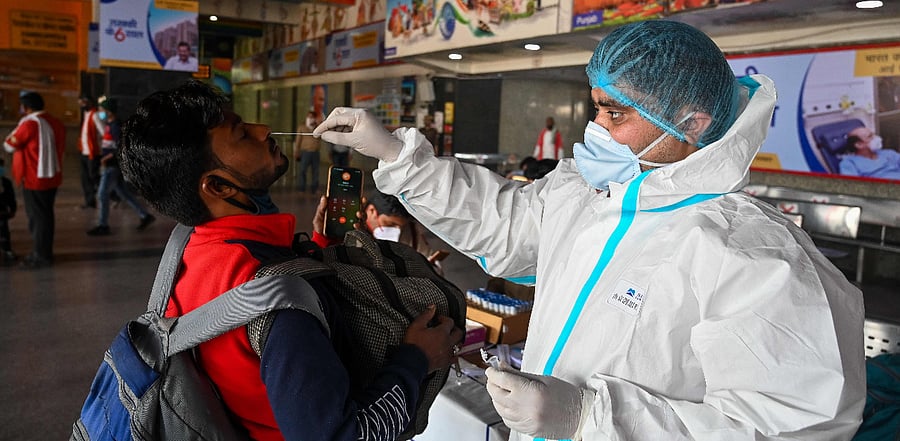 A medical worker takes a swab sample from a passenger for a Rapid Antigen Test (RAT) Covid-19  test at the railway station in New Delhi. Credit: AFP Photo