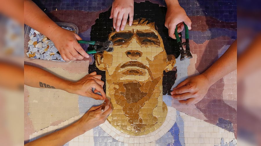 Gabriela Pereyra, Paula Soto, and Gonzalo Lopez Lluch, members of the cultural organization Comando Maradona, prepare a mosaic as an hommage to late Argentine soccer superstar Diego Armando Maradona, at their workshop, in Buenos Aires, Argentina February 24, 2021.  Credit: Reuters Photo