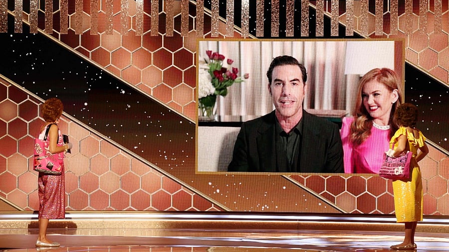 This handout photo courtesy of NBCUniversal shows Sacha Baron Cohen with Isla Fisher as he accepts the Best Picture – Musical/Comedy award for "Borat Subsequent Moviefilm" via video from Kristen Wiig (left, in character as Star) and Annie Mumolo (right, in character as Barb) at the 78th Annual Golden Globe Awards held at the Beverly Hilton Hotel on February 28, 2021. Credit: AFP
