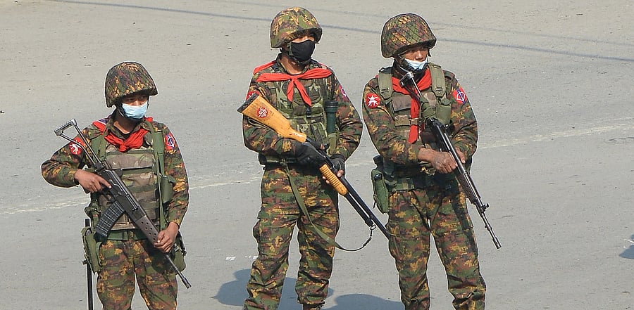 Soldiers carrying firearms look on as protesters hold a demonstration against the military coup. Credit: AFP Photo