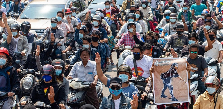 A man holds up a poster featuring protester Kyal Sin as people attend her funeral procession. Credit: AFP Photo
