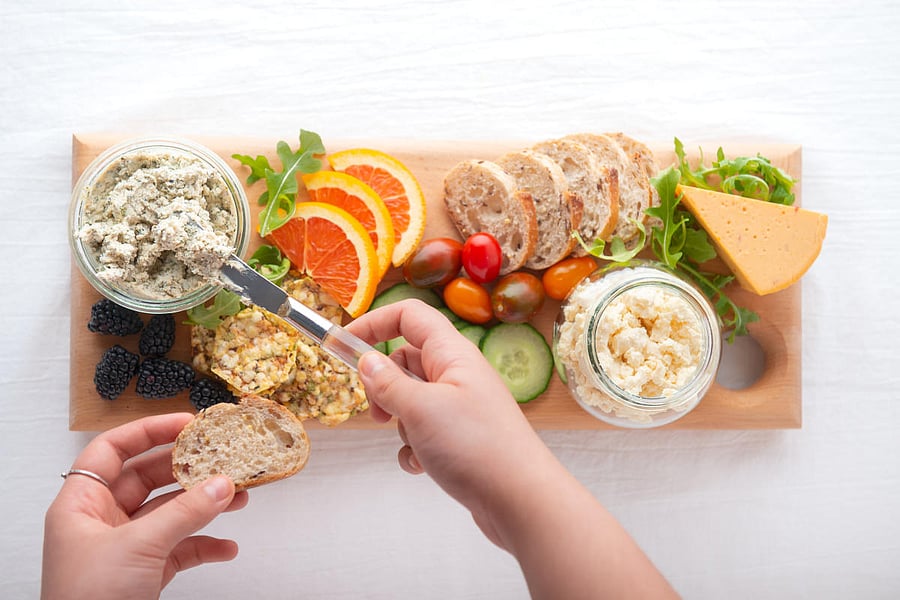 Personal perspective. Vegan boursin, feta and cheddar cheese in recycled jars. Raw fruit, berries, vegetables, whole grain bread and crackers on handmade reclaimed wood serving board.Cheese. Credit: Getty Images 