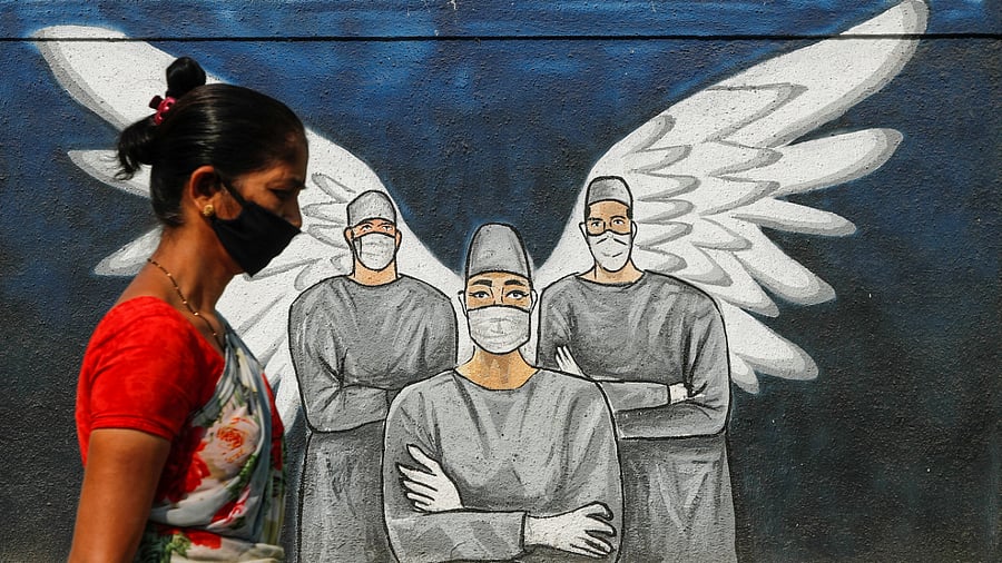 Woman wearing a protective mask walks past a graffiti amidst the spread of Covid-19, in Navi Mumbai. Credit: Reuters Photo