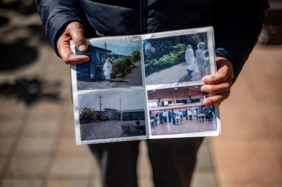 In this picture taken on February 28, 2021, church member Harumi Mottate holds a photo book showing pictures of her evacuation following the Fukushima Daiichi nuclear plant disaster. Credit: AFP photo.